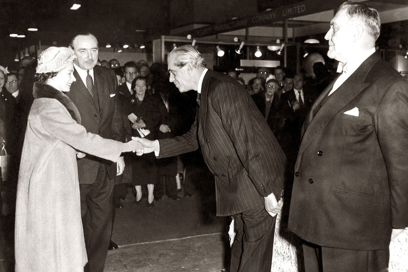 Black and white historical photograph showing a handshake between Franklin D. Roosevelt and Winston Churchill at the 1939 international exposition in Paris, with other figures in suits around them.